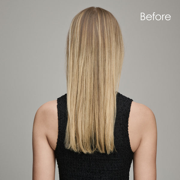 A woman in a black dress stands confidently before her hair extensions are applied, showcasing her natural hair length.
