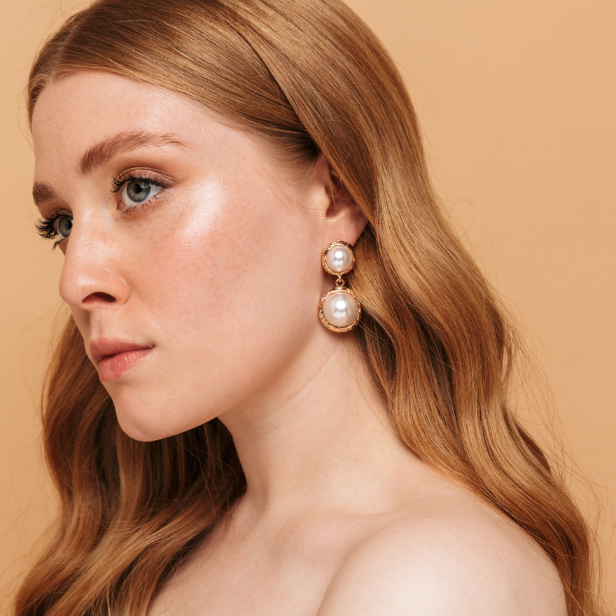 A woman adorned a pearl earring, elegantly displaying her hair extensions, radiates charm and style.