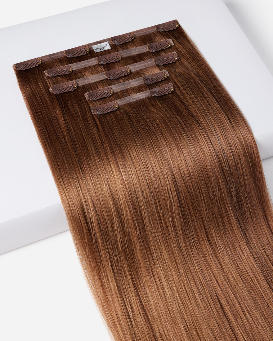 A set of brown clip-in hair extensions arranged neatly, highlighting their seamless blend with natural hair for added volume.