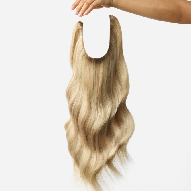 A woman's hand gracefully holding a long blonde wig, showcasing the beauty of hair extensions.