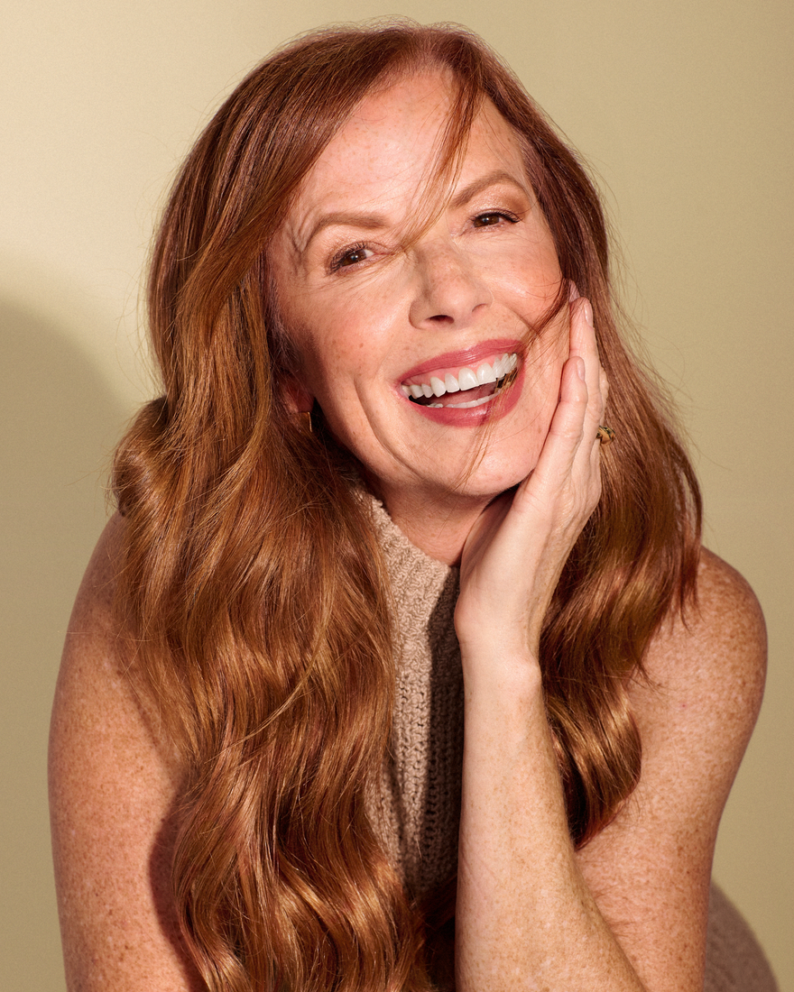 A woman with long red hair, enhanced by Hidden Crown extensions, smiles brightly, radiating joy and confidence.